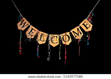 Welcome party banner. Bunting letters spelling the word welcome with celebration streamers isolated against black background. Black text written on card.