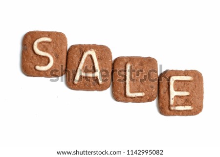 White letters on a chocolate cookie. The inscription "sale" concept of sales, discounts. Text SALE made with letters on cookies on a white background