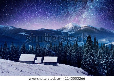 A small village on a snow covered mountain ridge in a moonlight. The starry sky above the carpathian mountains, fabulous views, new year's Christmas look, the Milky Way,