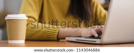Young woman working with the laptop on a desk in coffee shop. Young woman working on weekend with her laptop in a warm sunlight day. Laptop working in the coffee shop concept. Panoramic banner.