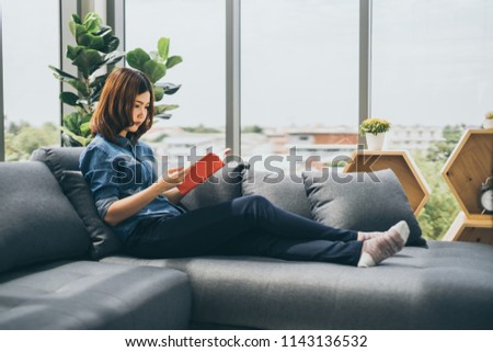 beautiful asian woman enjoy reading book on sofa home background
