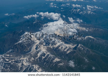 Aerial view of the Kazbek mountain and mountain range which partially covered by the snow on the top during the summer time