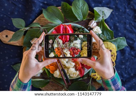 Smartphone food photography of vegetables Buddha Bowl for lunch or dinner. Woman hands takes trendy phone photo of food. Good for blogging or social media. Vegan vegetarian food