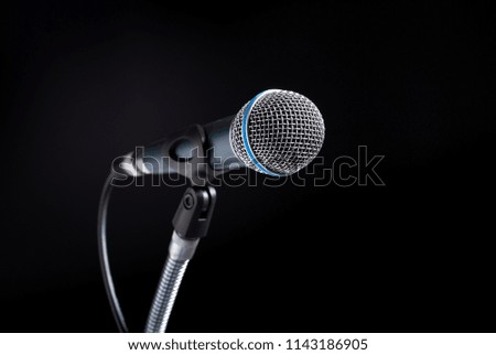 Audio green microphone on stand in black dark background.
