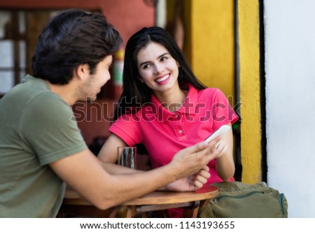 Young tourist couple in vacation booking hostel with mobile phone in restaurant