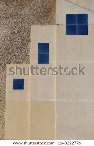 Close up outdoor view of part of a grey wall made of blue and white decorative elements. Graphic image with squares and rectangles. Colored facade with polygonal shapes. 