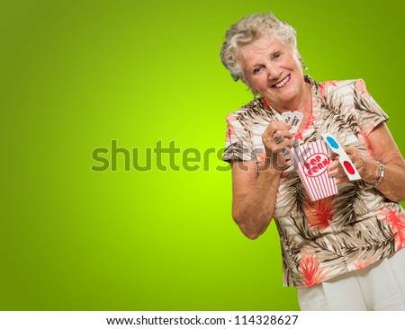 Portrait Of Senior Woman Holding 3d Glasses, Popcorn And Tickets On Green Background