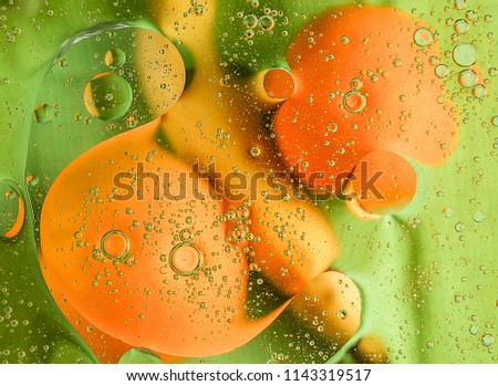 Two oranges and banana floating in water with oil drops. Close up.