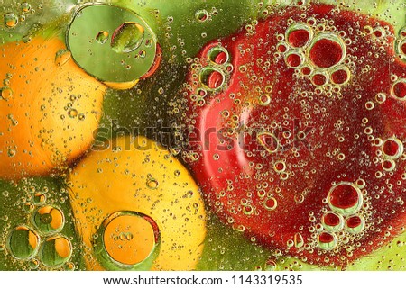 Two oranges and a red plate floating in water with oil drops.