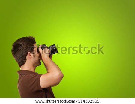 Young Man Holding Camera On Green Background