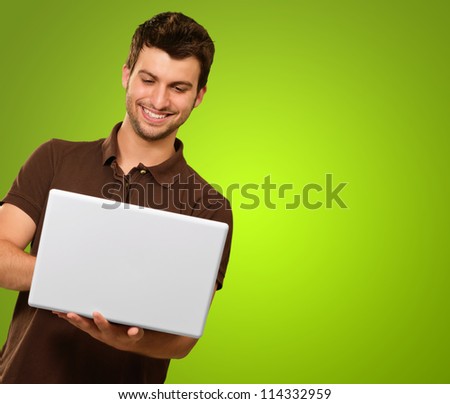 Happy Young Man Holding Laptop On Green Background