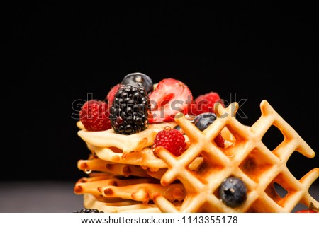 Photo of viennese wafers with berries pouring honey on black background