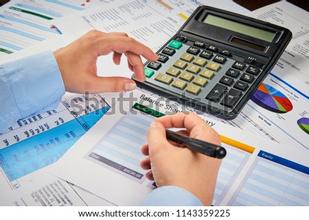 human hands write balance sheet summary on a background balances sheets with calculator Royalty-Free Stock Photo #1143359225