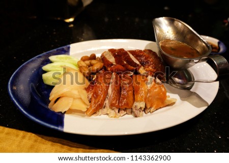 Roasted duck with gravy sauce in ceramic plate on black table.