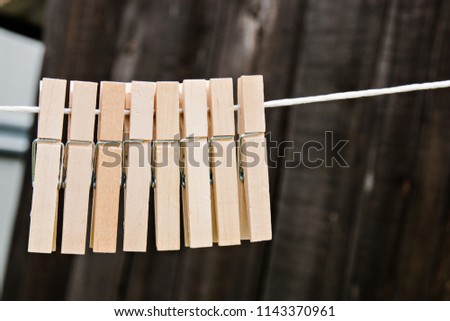 wooden clothespins hang on a rope on a wooden background.