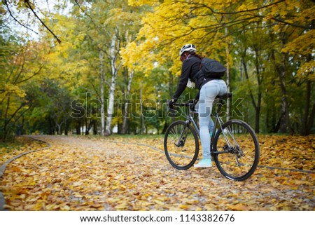 Photo of woman in helmet riding bicycle in autumn