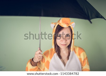 Girl with umbrella in a bright children's pajamas in the form of a kangaroo. emotional portrait of a student. costume presentation of children's animator. Slippers in the form of cat's paws.