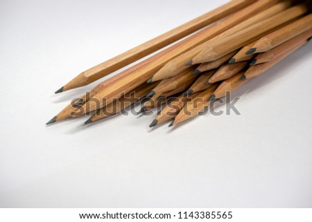 Many brown pencils are placed on paper.