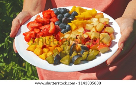 woman presenting a plate with sliced summer fruits