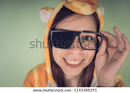 The girl in the broken sun protection glasses in a bright children's pajamas in the form of a kangaroo. emotional portrait of a student. costume presentation of children's animator. Slippers in the fo