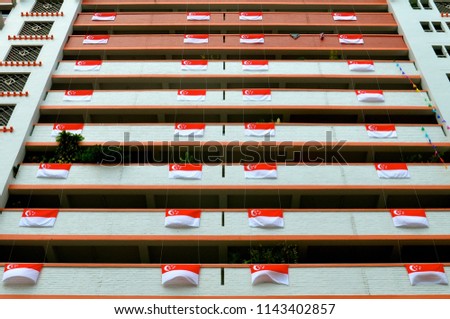 Singapore flags displayed in a regular and orderly arrangement, outside residential apartment blocks in celebration of national independence day, which is celebrated on 9th August each year. 