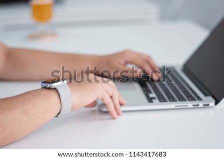 Girl wearing smartwatch using laptop indoors