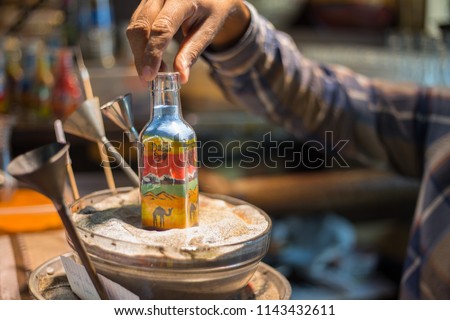 Making camel by sand in the souvenir sand bottle at the Madinat Jumeirah Souk, Dubai, UAE. Craftsman makes souvenirs in a bottle using colored sand
