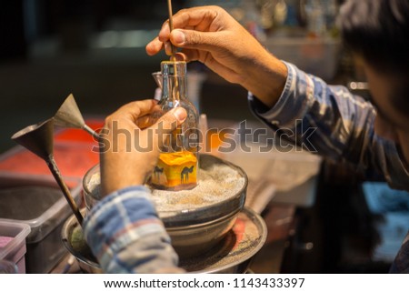 Making camel by sand in the souvenir sand bottle at the Madinat Jumeirah Souk, Dubai, UAE. Craftsman makes souvenirs in a bottle using colored sand
