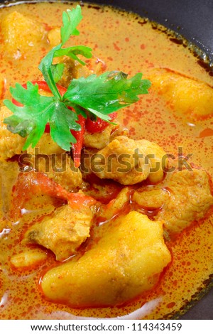 MUSLIM CURRY WITH CHICKEN TOPPING WITH PARSLEY AND CHILI IN BLACK BOWL