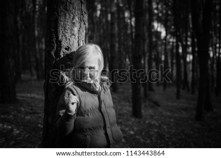 A gorgeous little girl poses for a picture in a forest as the sunlight peaks though onto a tree