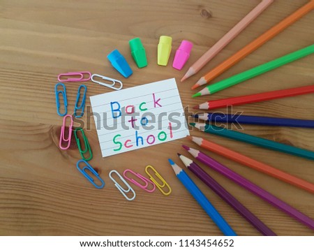 Back to school sign with colored pencils, paper clips and erasers laying on a wooden desk, School supplies, Back to school