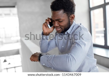 business, technology, communication and people concept - african american businessman calling on smartphone at office