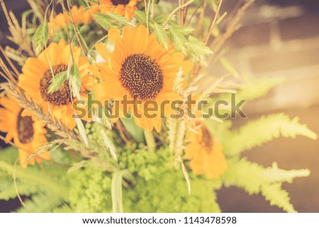 Bouquet of sunflowers in a glass vase on a wooden table. Retro toned.