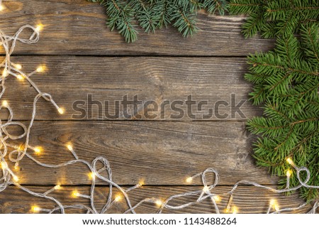 Christmas close-up of Christmas tree branches and Chistmas lights on vintage wooden background. Top view of a Christmas workplace. New Year frame or Xmas Mockup. Royalty-Free Stock Photo #1143488264