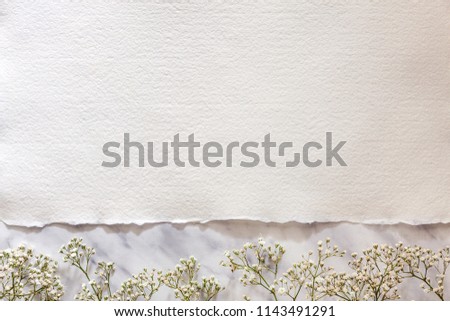 Copy space from white handmade paper on a marble table with white flowers