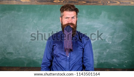 Pay attention to your behaviour and manners. Teacher behaves unprofessionally. Man bearded teacher or educator eats necktie chalkboard background. Teacher etiquette tips modern education professional.