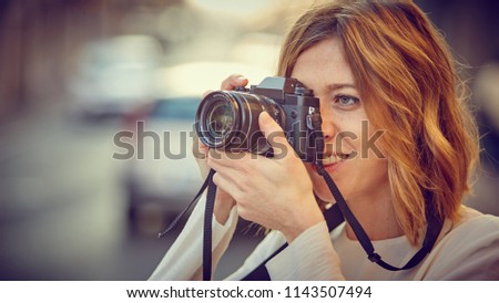 Girl with mirrorless take a photo on the street of the city