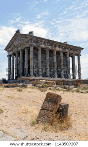 Khachkar on the background of Garni pagan temple in Armenia