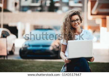 Young woman sitting on a bench and using laptop.