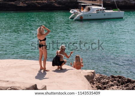 young women on the shore take pictures of the sea by telephone