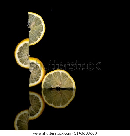 Creatively balanced fresh lemon fruit slices on dark background. Unusual photo. Seem to defy gravity. Isolated on black