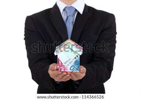 Man holding house made from money