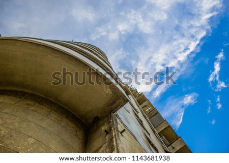 concrete common house wall facade from below on blue sky clouds background 
