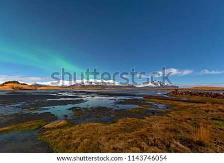 Winter lake near mountain in Hofn, Iceland. Northern lights and blue sky background. Winter season landscape background