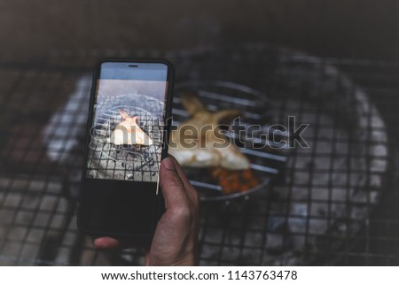 Chef take picture with cell phone of grilled hamachi kama fish cheek with charcoal in matte color
