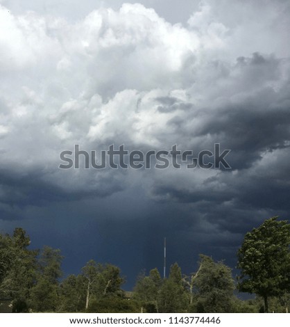 Ominous rain clouds with trees and radio tower in background