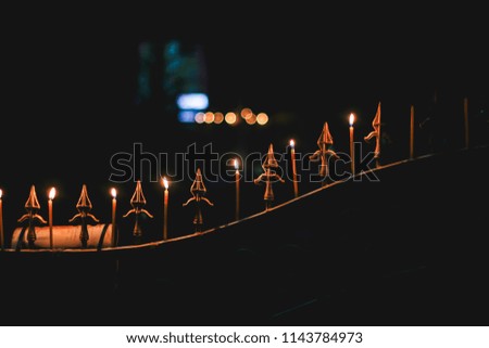 Abstract blurred candle by the wind in the important day of Religion Buddhism on fence house of thai people with blurred bokeh background at night.Vintage night Tone.