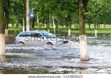 The car, moving on a flooded road in the city through the crosswalk