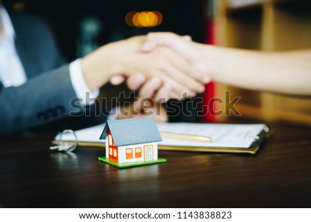 Wooden house on the table background with real estate agents and customer shaking hands after signing contract for realty purchase .Concept mortgage loan approval  home loan and insurance concept. Royalty-Free Stock Photo #1143838823