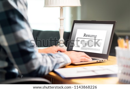 Man writing resume and CV in home office with laptop. Applicant searching for new work and typing curriculum vitae for application. Job seeking, hunt and unemployment. Mock up text in computer screen. Royalty-Free Stock Photo #1143868226